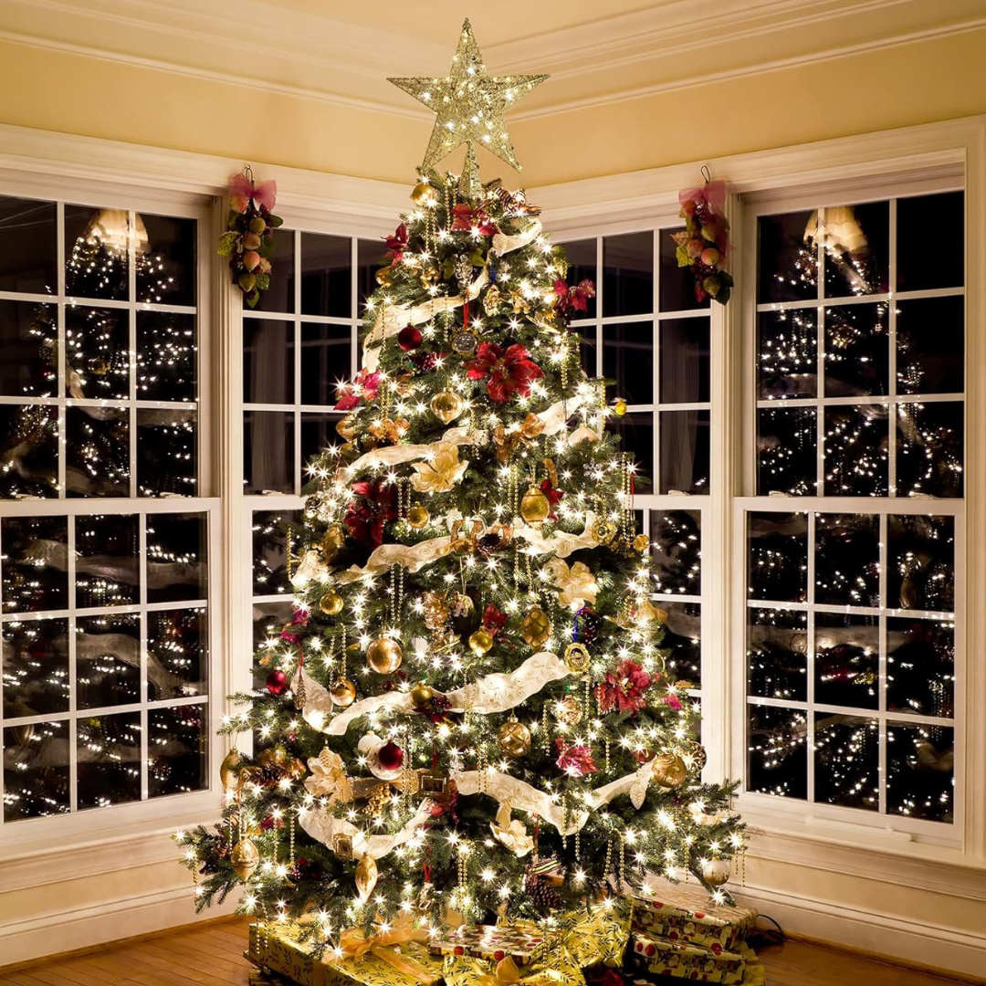 Decorated Christmas tree with lights and ornaments in a room with large windows showing a cityscape at night.