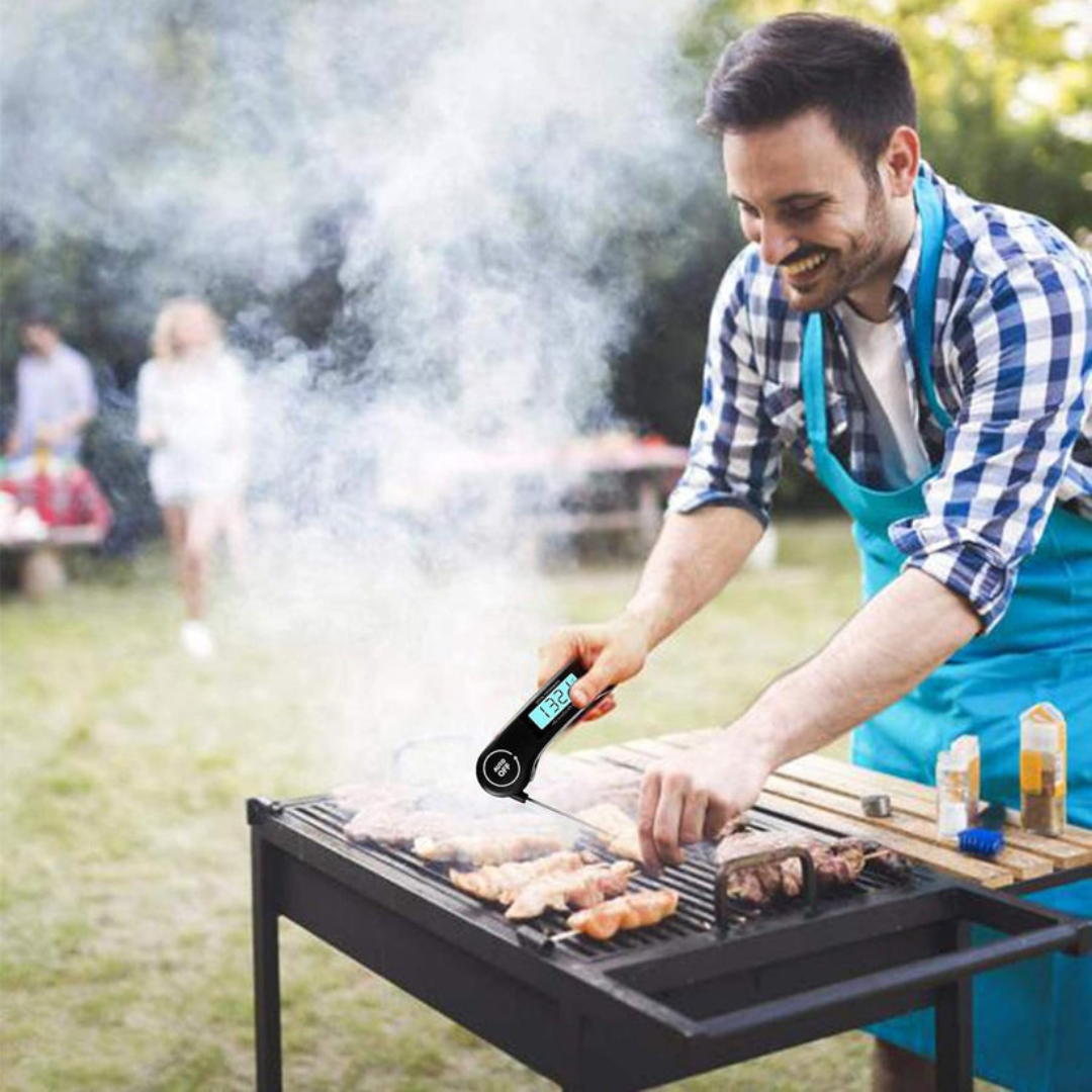 Man grilling outdoors using a digital thermometer, with family in the background