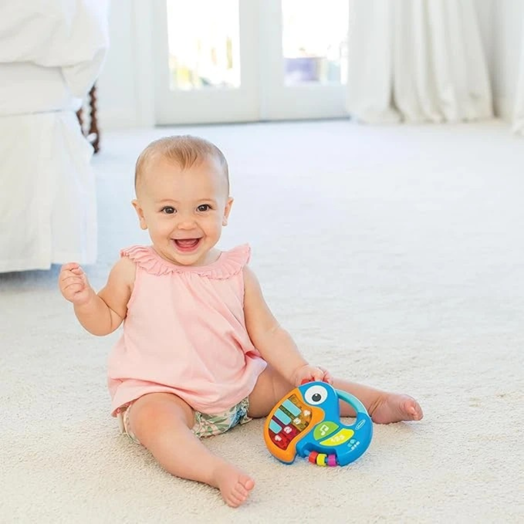 Baby sitting on a carpeted floor holding a colorful toy