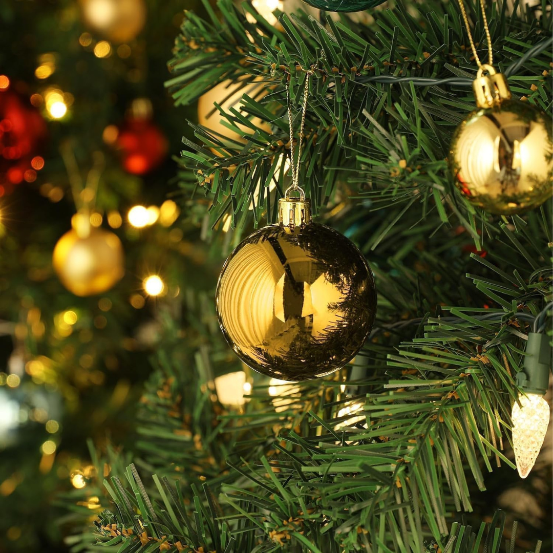 Gold Christmas ornament on a tree with blurred lights in the background