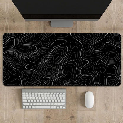 Black and white patterned desk mat on a wooden desk with a computer monitor, keyboard, and mouse.