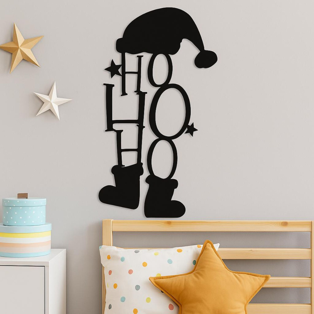 Decorative wall art with 'HO HO HO' and jester hat design on a gray wall above a bed.