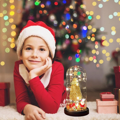 Child wearing a Santa hat with a Christmas tree ornament in a glass dome, surrounded by lights and presents.