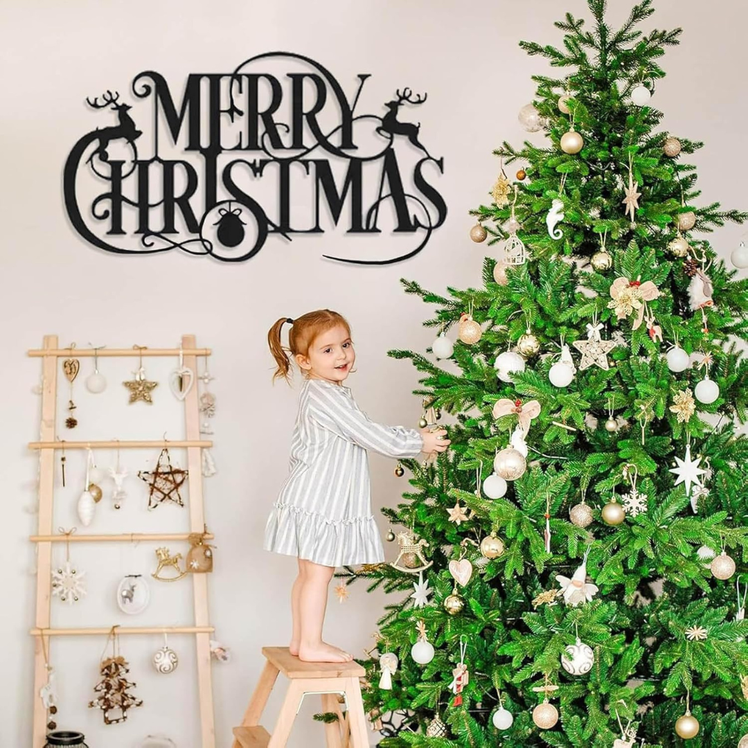 Child decorating a Christmas tree with ornaments, next to a 'Merry Christmas' sign.